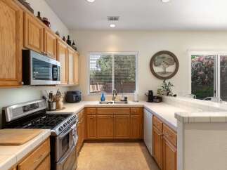 This charming kitchen features warm oak cabinetry and a spacious double sink beneath a large window, perfect for natural light.