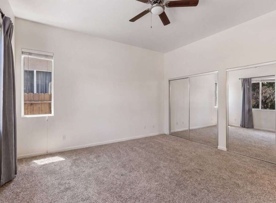 This spacious bedroom features plush carpeting and ample natural light streaming in from the large windows.