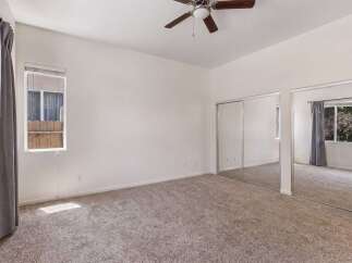 This spacious bedroom features plush carpeting and ample natural light streaming in from the large windows.
