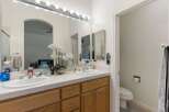 This spacious bathroom features a double vanity with white tile countertops and ample storage space in the light oak cabinets.