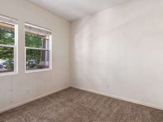 This empty room features a neutral color palette with beige carpeting and off-white walls, creating a blank canvas for personalization.