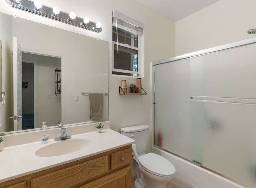 This bathroom features a spacious vanity with a large mirror and ample lighting, perfect for your morning routine.