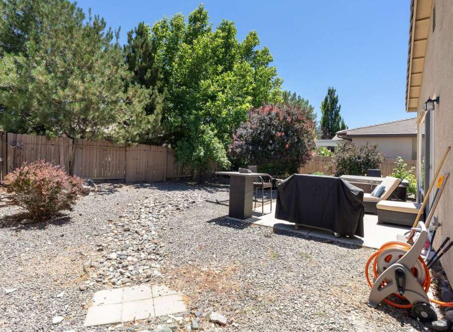 Enjoy outdoor living in this spacious backyard, featuring a covered grill area perfect for summer cookouts.