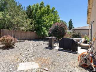 Enjoy outdoor living in this spacious backyard, featuring a covered grill area perfect for summer cookouts.