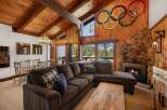 Experience rustic charm in this mountain lodge living room, featuring a grand stone fireplace and a vaulted wood-paneled ceiling with exposed beams.
