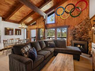 Experience rustic charm in this mountain lodge living room, featuring a grand stone fireplace and a vaulted wood-paneled ceiling with exposed beams.