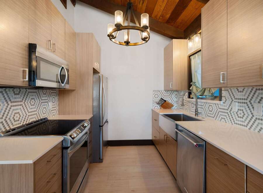 This modern kitchen features sleek, light wood cabinetry complemented by a striking hexagonal tile backsplash.
