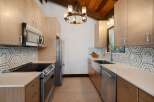 This modern kitchen features sleek, light wood cabinetry complemented by a striking hexagonal tile backsplash.