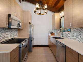 This modern kitchen features sleek, light wood cabinetry complemented by a striking hexagonal tile backsplash.