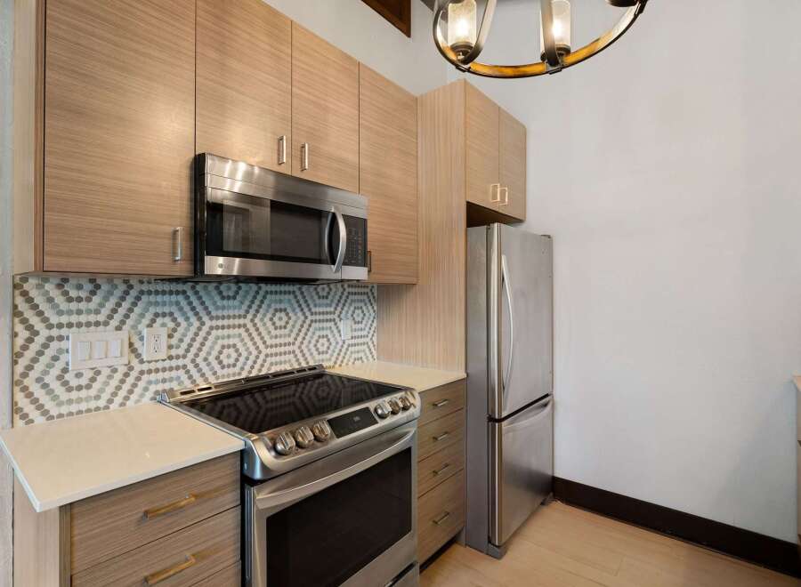 Discover this modern kitchen featuring sleek, light wood cabinetry and a stylish hexagonal tile backsplash.