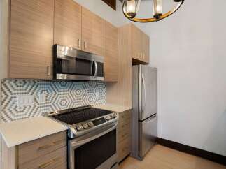 Discover this modern kitchen featuring sleek, light wood cabinetry and a stylish hexagonal tile backsplash.