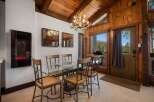 Experience rustic charm in this dining area featuring a unique antler chandelier and a sleek glass-top table.