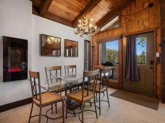 Experience rustic charm in this dining area featuring a unique antler chandelier and a sleek glass-top table.