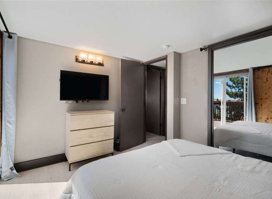 This bedroom offers a modern and comfortable retreat, featuring a wall-mounted TV above a sleek dresser for entertainment.