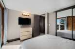 This bedroom offers a modern and comfortable retreat, featuring a wall-mounted TV above a sleek dresser for entertainment.