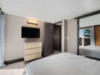 This bedroom offers a modern and comfortable retreat, featuring a wall-mounted TV above a sleek dresser for entertainment.