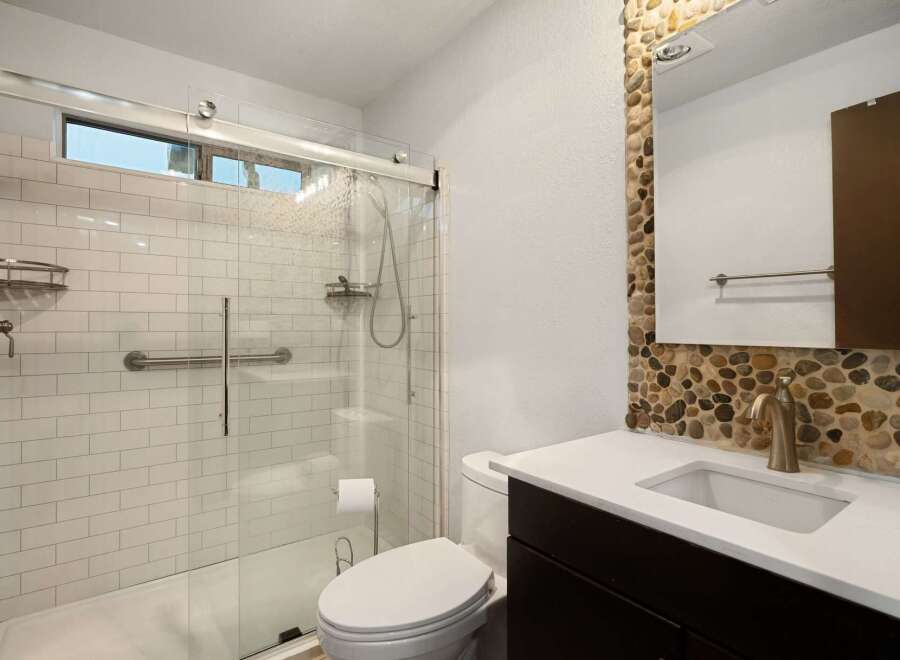 This modern bathroom features a spacious walk-in shower with white subway tile and a convenient grab bar.