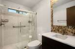 This modern bathroom features a spacious walk-in shower with white subway tile and a convenient grab bar.