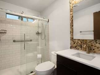 This modern bathroom features a spacious walk-in shower with white subway tile and a convenient grab bar.