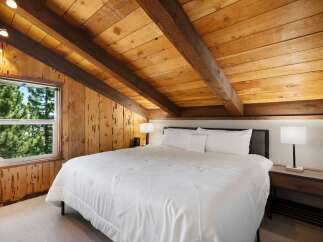 Experience rustic charm in this cozy bedroom featuring a plush king-sized bed with crisp white linens.