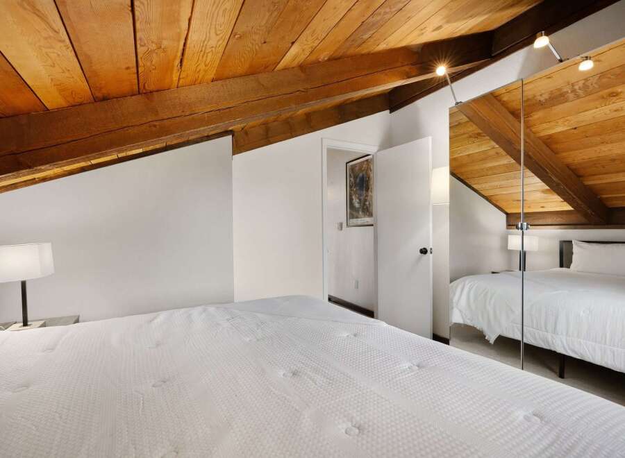Experience rustic charm in this attic bedroom, featuring a beautifully exposed wooden beam ceiling that adds warmth and character.