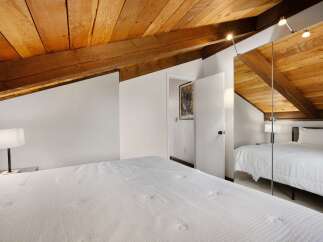 Experience rustic charm in this attic bedroom, featuring a beautifully exposed wooden beam ceiling that adds warmth and character.