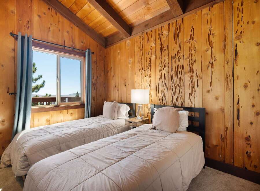 Experience rustic charm in this cozy bedroom featuring two twin beds adorned with plush linens and decorative pillows.