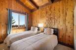 Experience rustic charm in this cozy bedroom featuring two twin beds adorned with plush linens and decorative pillows.