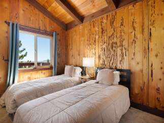 Experience rustic charm in this cozy bedroom featuring two twin beds adorned with plush linens and decorative pillows.