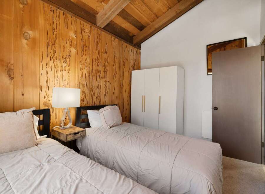 Experience rustic charm in this cozy bedroom featuring a vaulted wood-paneled ceiling and exposed beams.