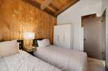 Experience rustic charm in this cozy bedroom featuring a vaulted wood-paneled ceiling and exposed beams.