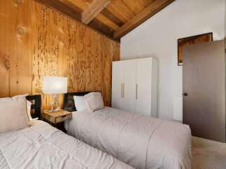 Experience rustic charm in this cozy bedroom featuring a vaulted wood-paneled ceiling and exposed beams.