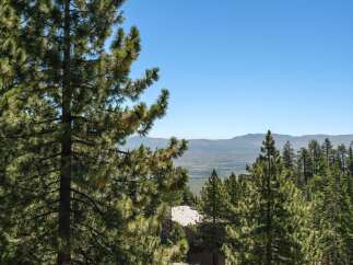 Experience breathtaking panoramic views from this stunning property, nestled amidst lush pine trees.