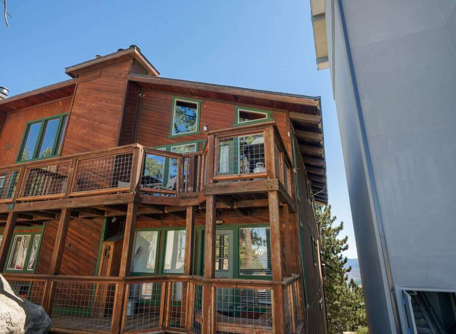 Experience mountain living in this stunning wooden home featuring multiple levels of decks with wire railings, perfect for enjoying the scenic views.