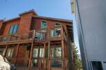 Experience mountain living in this stunning wooden home featuring multiple levels of decks with wire railings, perfect for enjoying the scenic views.