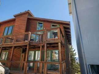 Experience mountain living in this stunning wooden home featuring multiple levels of decks with wire railings, perfect for enjoying the scenic views.
