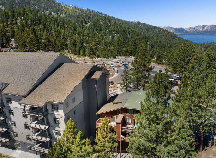 Experience luxury mountain living in this stunning property, featuring modern architecture with multiple balconies offering breathtaking views of the surrounding pine forest and distant lake.