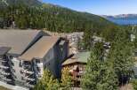 Experience luxury mountain living in this stunning property, featuring modern architecture with multiple balconies offering breathtaking views of the surrounding pine forest and distant lake.