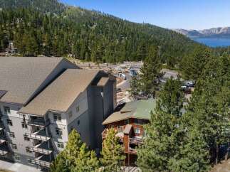 Experience luxury mountain living in this stunning property, featuring modern architecture with multiple balconies offering breathtaking views of the surrounding pine forest and distant lake.