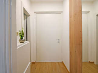 Step into this inviting hallway featuring a sleek white door and warm wooden flooring.
