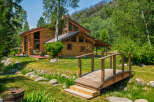 Experience rustic charm in this stunning log cabin nestled amidst lush greenery and a serene water feature.