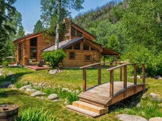Experience rustic charm in this stunning log cabin nestled amidst lush greenery and a serene water feature.