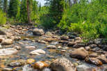 Discover a serene mountain retreat with a crystal-clear river flowing through a lush forest.