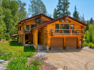 Experience rustic luxury in this stunning log home, nestled amidst lush greenery and mature trees.