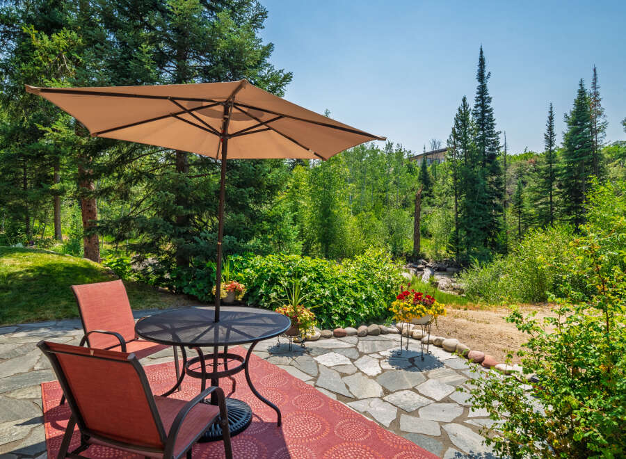 Enjoy outdoor living on this charming patio featuring a round metal table with two chairs and a large umbrella, perfect for al fresco dining.