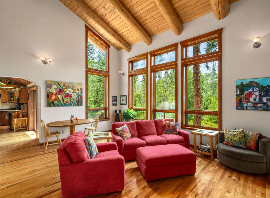 Experience the warmth of this inviting living space, featuring a vaulted wood-beam ceiling and expansive windows that flood the room with natural light.