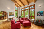 Experience the warmth of this inviting living space, featuring a vaulted wood-beam ceiling and expansive windows that flood the room with natural light.