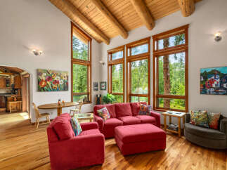 Experience the warmth of this inviting living space, featuring a vaulted wood-beam ceiling and expansive windows that flood the room with natural light.