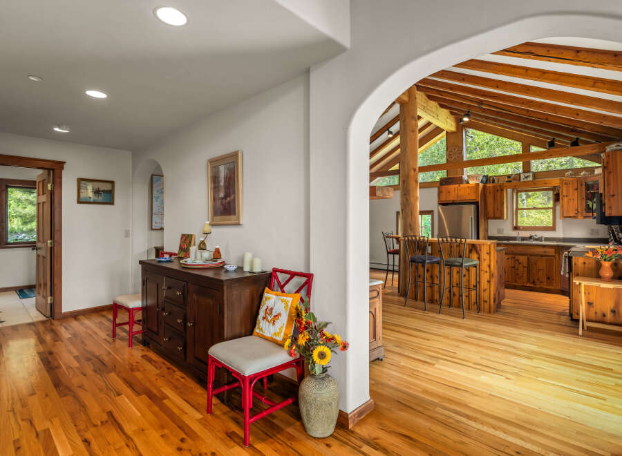 Step into a charming home featuring a spacious open-concept living area with a stunning vaulted ceiling and exposed wooden beams.