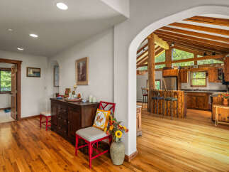 Step into a charming home featuring a spacious open-concept living area with a stunning vaulted ceiling and exposed wooden beams.